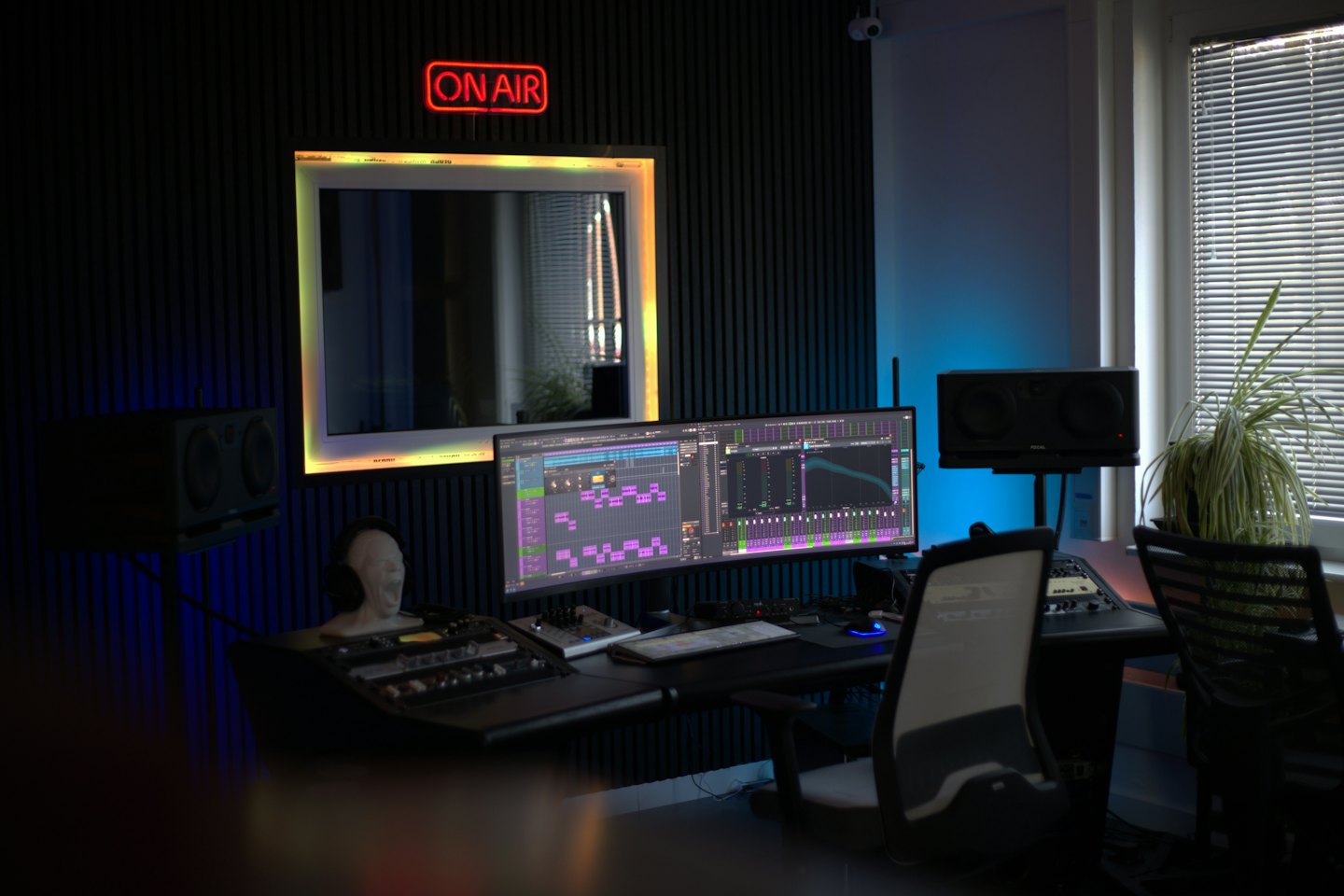 Musikproduktionsstudio mit Ultrawide-Monitor und Mischpult.