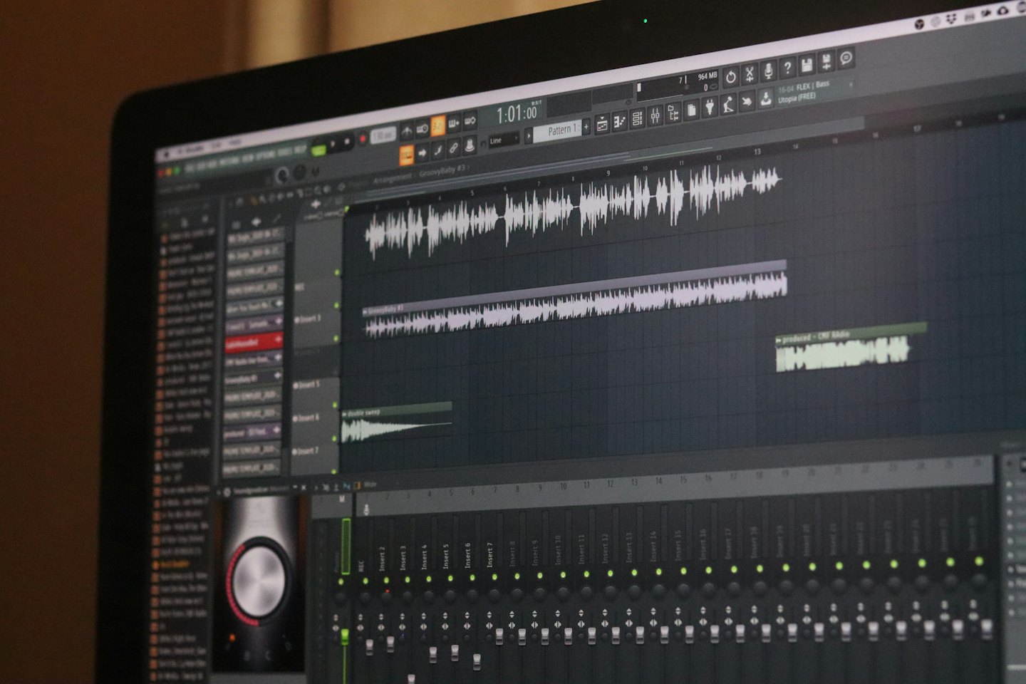 Laptop-Bildschirm mit Musikproduktionssoftware, Wellenformen und Schiebereglern.