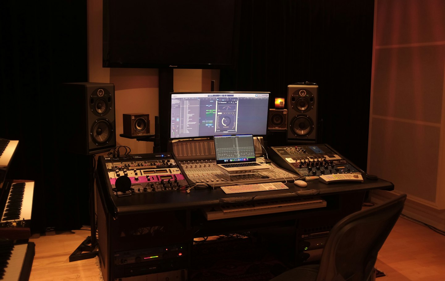 Ein moderner Musikproduktionsschreibtisch mit Audiogeräten und Computern.